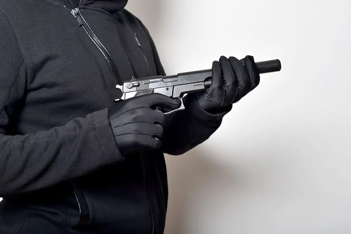 person-with-gloves-holding-a-handgun-with-silencer