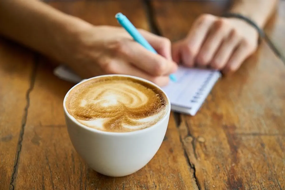 coffee-cup-and-person-taking-notes-in-background