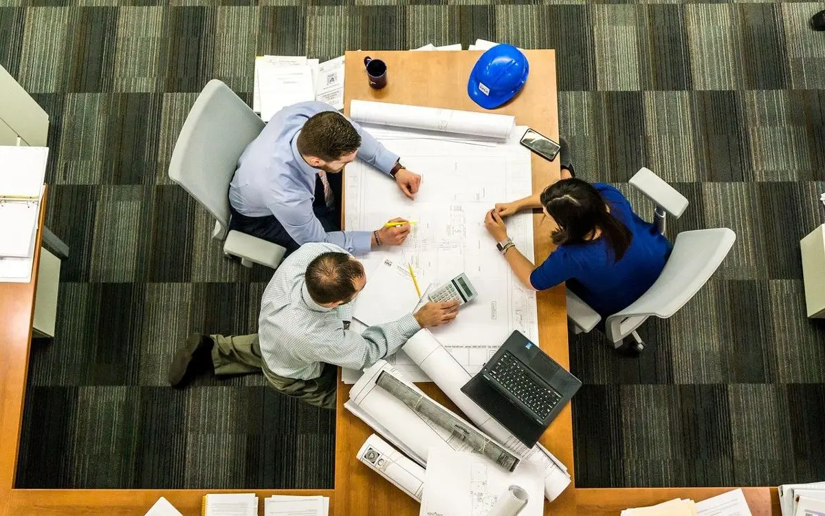 two-men-and-one-woman-sitting-around-table-planning-project