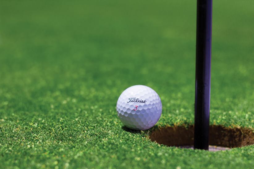 A golf ball on a green course up close.