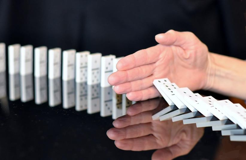 hand-stopping-falling-dominoes