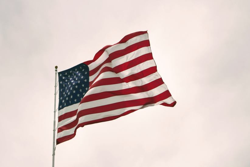 The flag of the United States flying in the air.