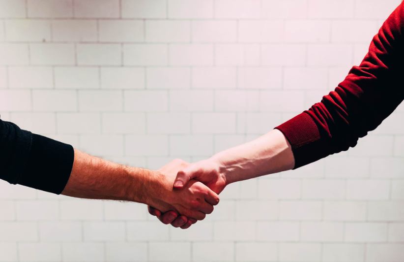 Two people shaking hands in a partnership confirmation.
