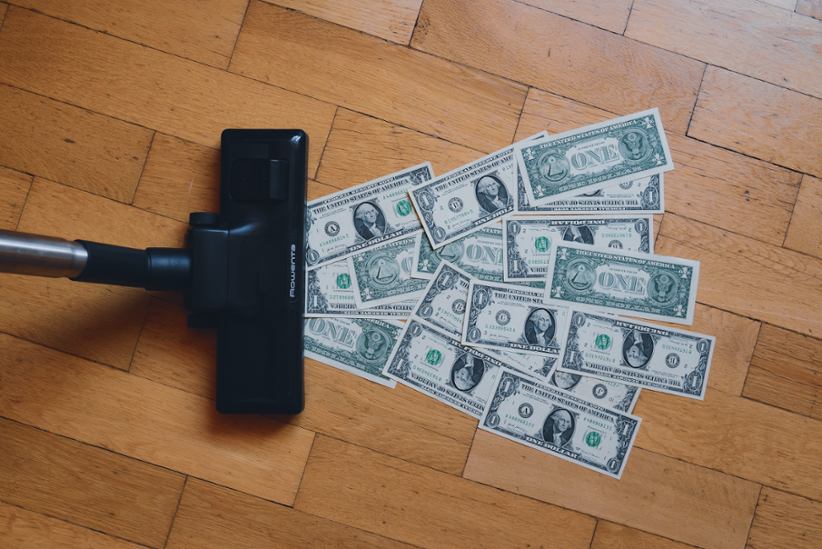 A vacuum cleaner vacuuming up dollar bills.