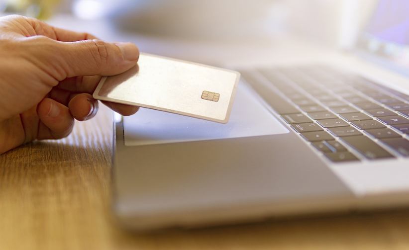 Close-up-photo-man-holding-credit-card-over-a-laptop