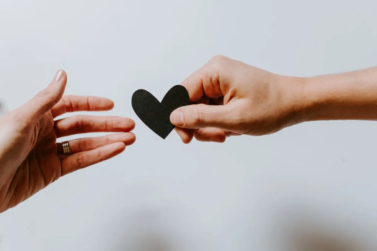 A person passing on a black paper-cut heart.