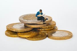 A person sitting on top of a mountain of coins.