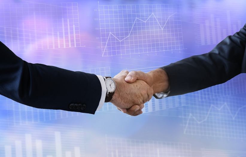 two-businessmen-shaking-hands-finance-graphs-background