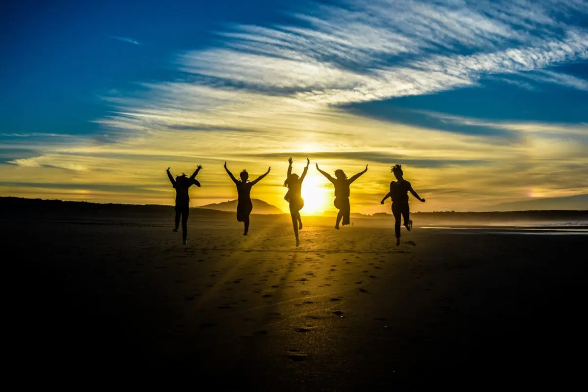 A bunch of people jumping in the sunset.