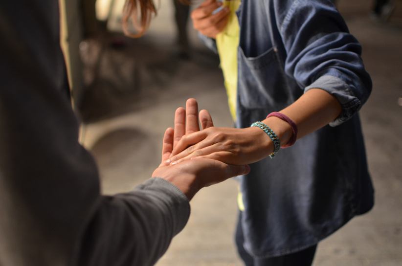 Two people reaching out with a hand to each other.