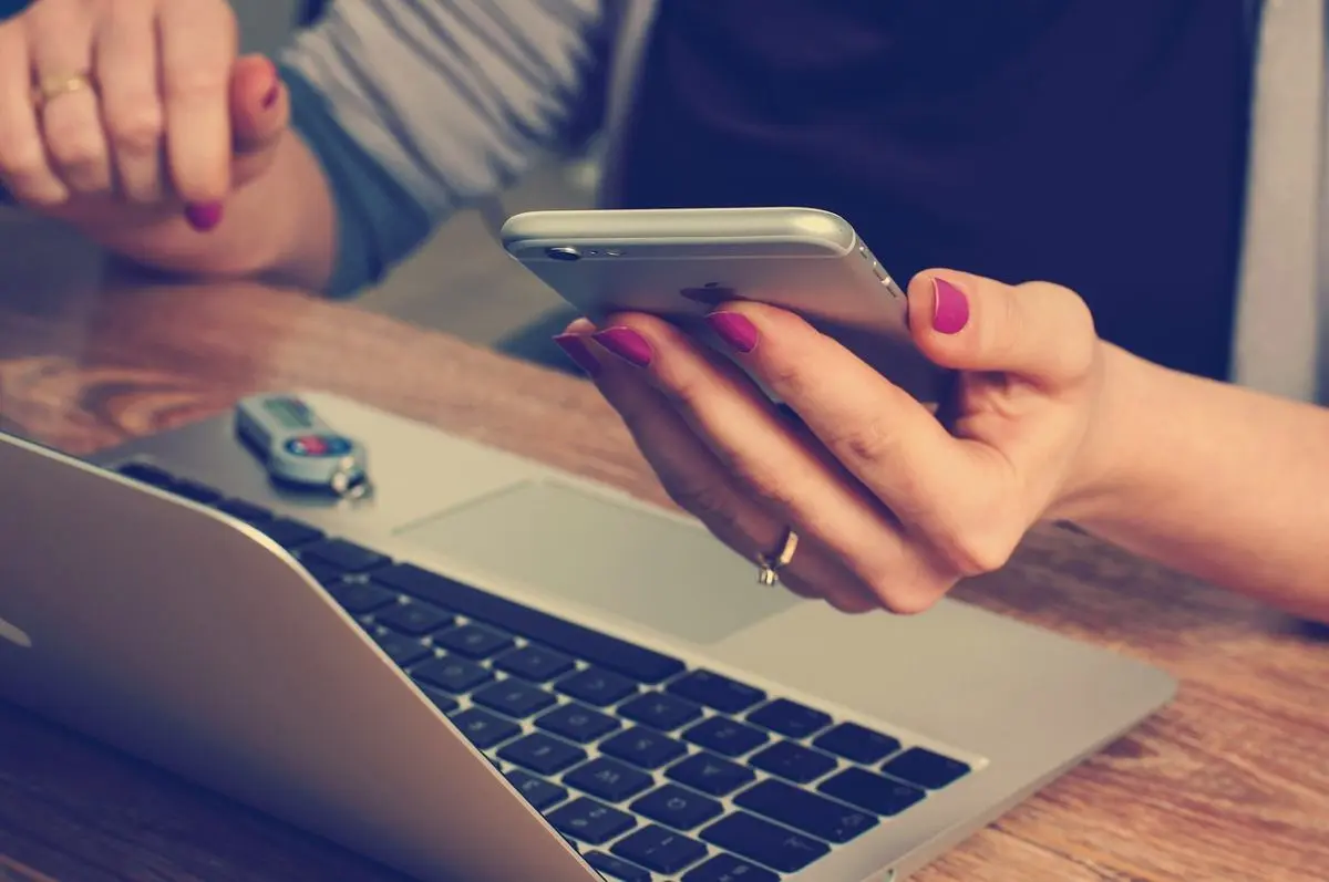 woman-holding-smartphone-in-front-of-laptop