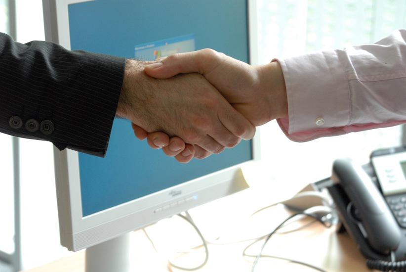 businessmen-shake-hands-on-office-background