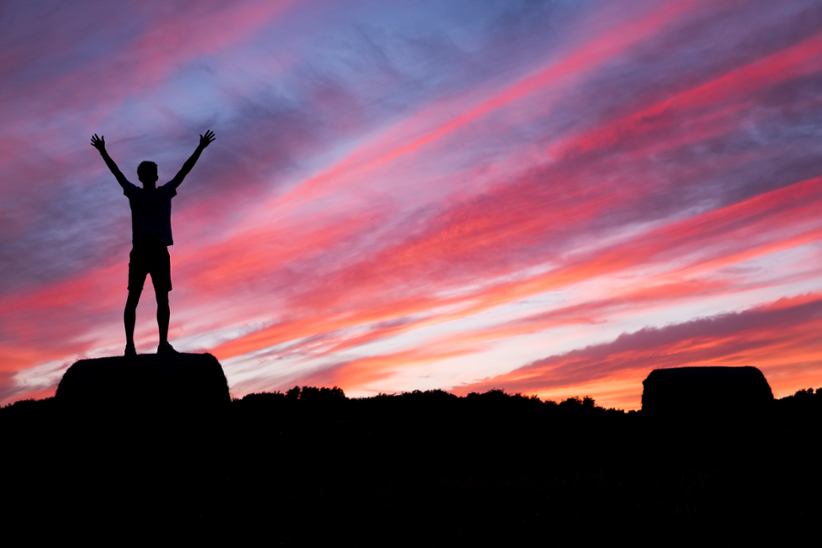 A man celebrating his success climbing a rock.