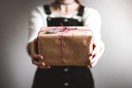 A person giving over a gift box.