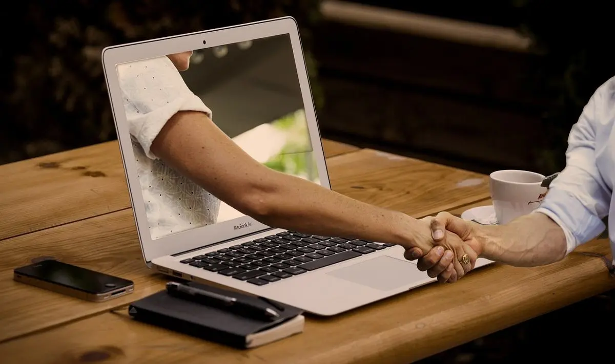 businessman-and-businesswoman-shake-hands-through-a-computer-screen