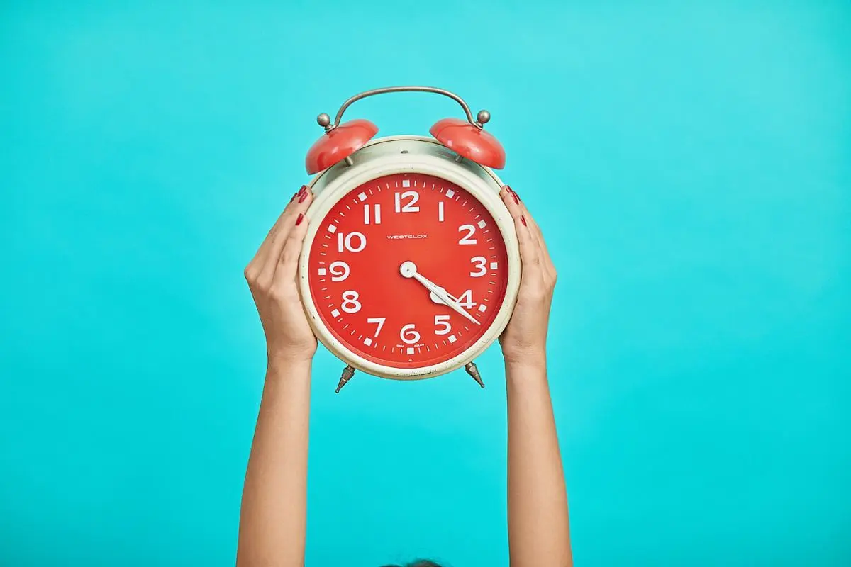 A standard clock held by two hands.