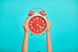 A standard clock held by two hands.