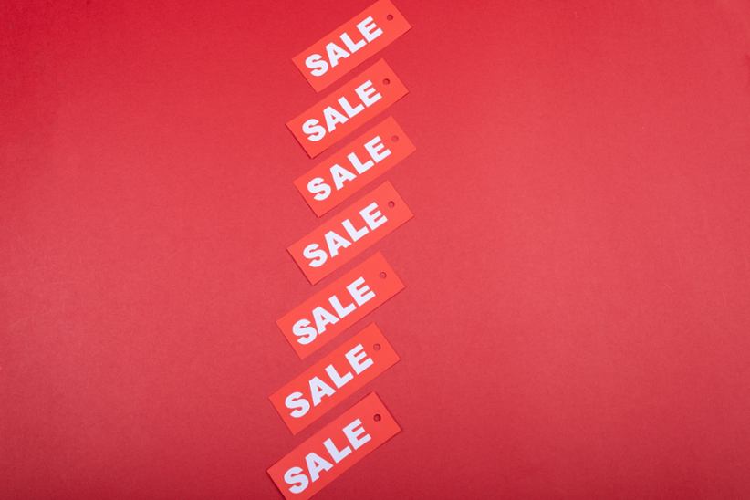 A picture that has many sale signs on a red backdrop.
