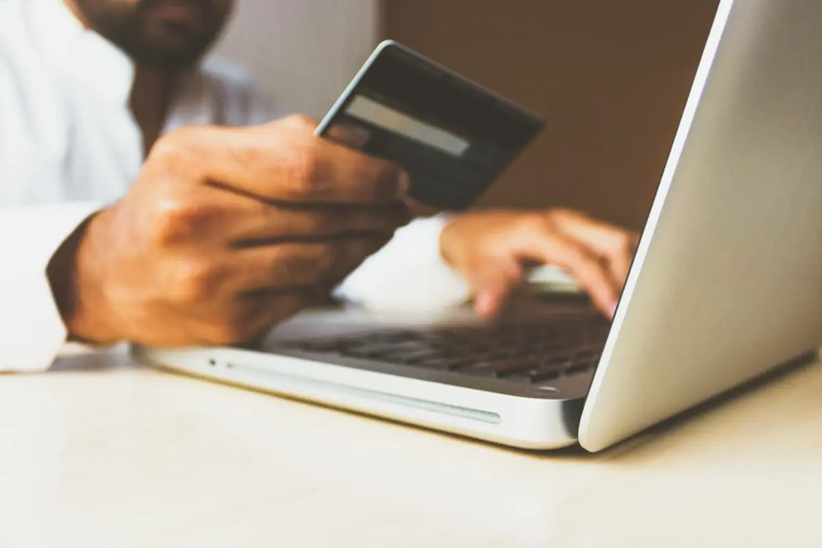 man-holding-credit-card-in-front-of-laptop