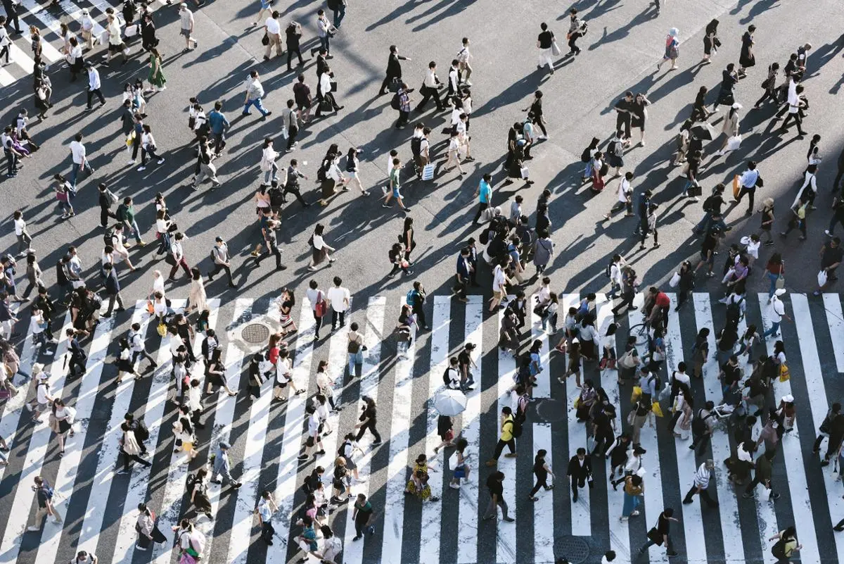 A bunch of people crossing a zebra.