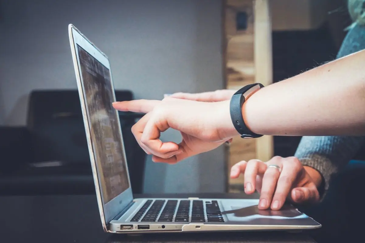 Two people pointing at a PC