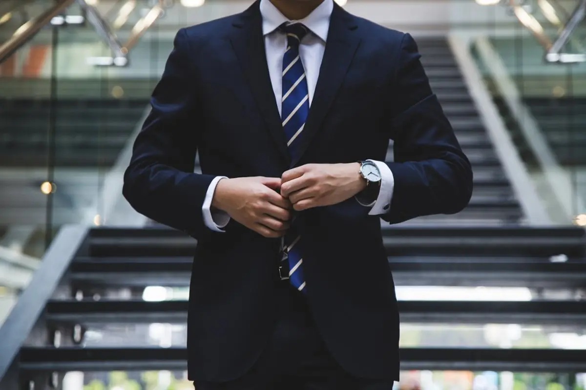 A man in suit going down the escalator.