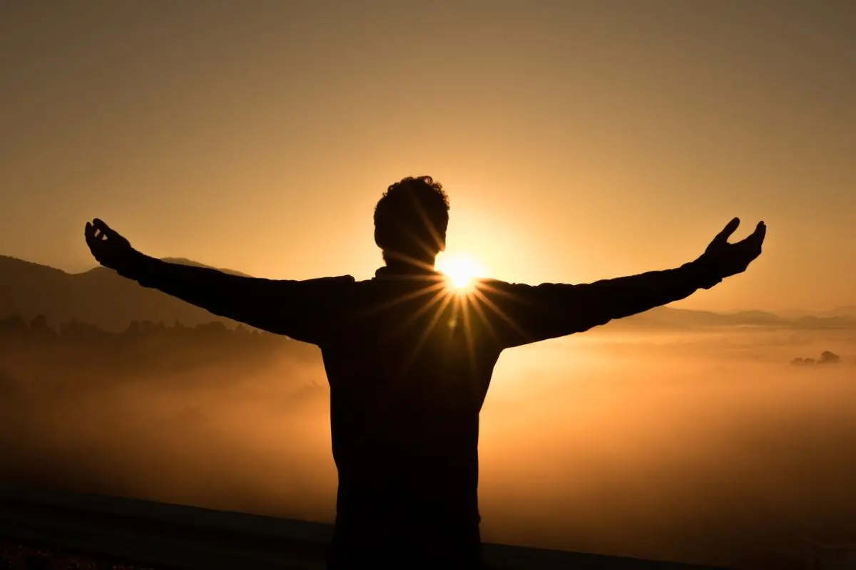 A man cheering at the sun.