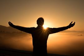 A man cheering at the sun.