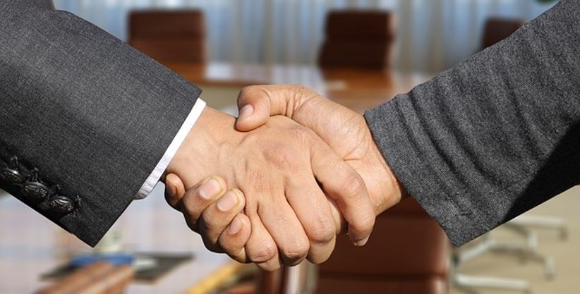 businessmen-shake-hands-office-background