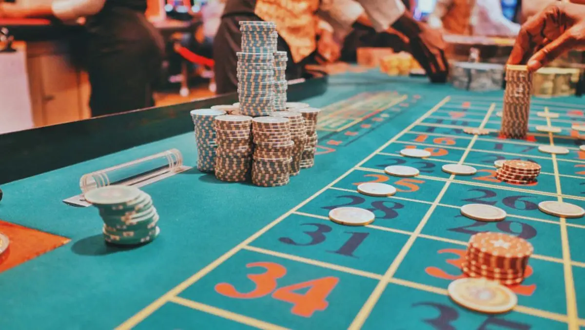 Chips on a casino roulette table with people playing.