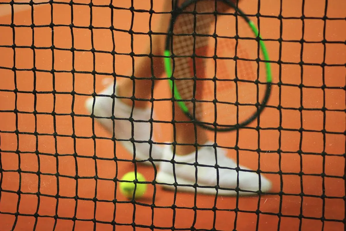 A tennis player walking by the court's net in the middle.